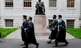 Nieuwe afgestudeerden passeren het beeld van John Harvard, eind mei. 
