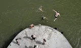 Zwemmers in Nijmegen. Mensen springen van een pijler van de spoorbrug, hoewel het is verboden om daar te zwemmen.