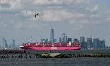 Een containerchip van Ocean Network Express (ONE) vaart langs de skyline van Manhattan terwijl het de haven van New York verlaat.